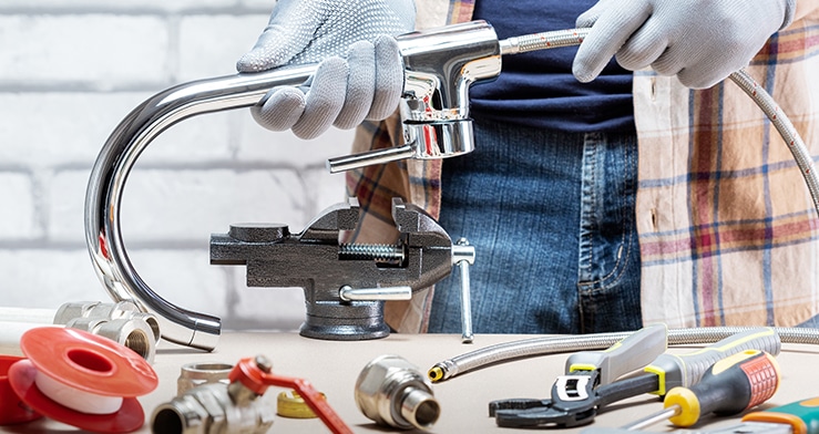 Plumber with tool set inspecting a sink.